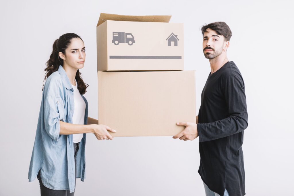 “Young couple struggling with moving boxes during home relocation – representing the challenges of choosing the right moving company in Kolkata”