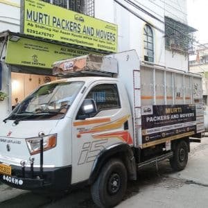 A commercial moving truck branded with Murti Packers and Movers parked outside their storefront, offering professional packing and moving services in Baguiati.
